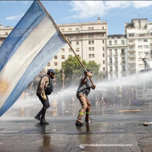 Manifestante levanta la bandera argentina en medio de la represión